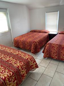 three beds in a room with red comforters at Shore Beach Houses - 38 Dupont Avenue in Seaside Heights