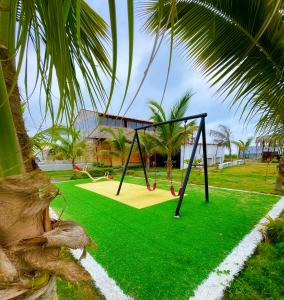 a swing set in a park with green grass at Hostal Tropicoco in Playas