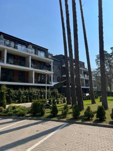 a building with palm trees in front of it at Sosnowe Apartamenty - Marina in Augustów