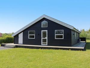 ein schwarzes Haus mit einem Rasenplatz davor in der Unterkunft 8 person holiday home in Hadsund in Hadsund