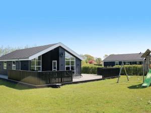 ein schwarzes Haus mit Spielplatz und Schaukel in der Unterkunft 8 person holiday home in Hadsund in Hadsund