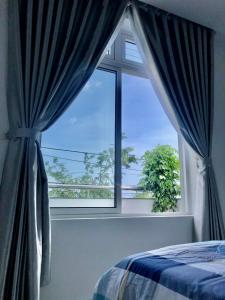 sypialnia z oknem z niebieskimi zasłonami i łóżkiem w obiekcie Sky House Apartment w Tam Kỳ