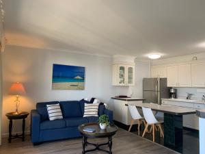 a living room with a blue couch and a kitchen at Waikiki Banyan 1909 Amazing Views and Just Steps to the Beach in Honolulu