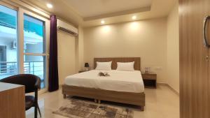 a bedroom with a bed and a desk and a window at Covie Gurugram 70 in Gurgaon