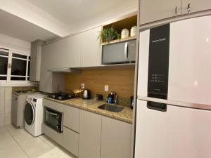 a kitchen with white cabinets and a sink and a dishwasher at Apartamento proximo a Rua Coberta GIJOCA 01 in Gramado