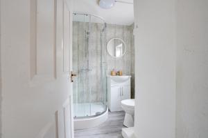 uma casa de banho branca com um chuveiro e um WC. em Modern and Spacious 3-Bedroom House - Free Parking, Fast Wi-Fi, Ideal for up to 7 Guests em Houghton le Spring