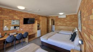 Un dormitorio con una cama, un escritorio y un televisor. en Merino Motor Inn, en Saint George 47 fotos más