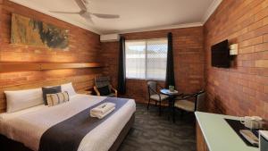 1 dormitorio con 1 cama en una habitación con paredes de ladrillo en Merino Motor Inn en Saint George