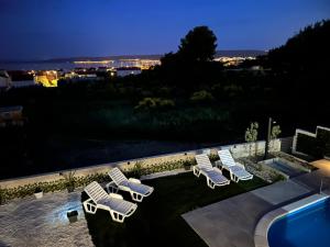 a group of lounge chairs sitting on a lawn at night at Villa Marta 3 bedrooms, 2 baths and pool in Kastel Stafilic