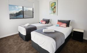 three beds in a room with white walls at Quattro On Young in Newcastle