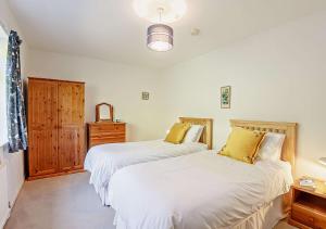 two beds in a bedroom with white sheets and yellow pillows at Llys Pennant in Gwytherin