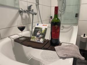 a bottle of wine and a book and wine glass on a bath tub at 4-Sterne Ferienwohnung Krill in Bad Wurzach +8 photos