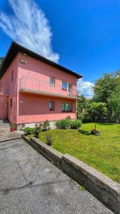 a pink house with a grass yard in front of it at Guest House Bosnian House in Sarajevo