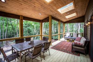 a screened in porch with a table and chairs at Red Bird Retreat in Beech Mountain