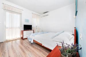 a white bedroom with a bed and a television at BANKO APARTMENTS & Rooms in Rovinj