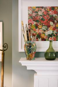 a vase on a mantle with a painting of flowers at Gardener's House - Hawarden Estate in Hawarden
