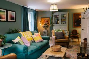 a living room with a blue couch and chairs at Gardener's House - Hawarden Estate in Hawarden