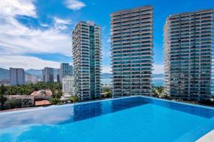 a swimming pool on the roof of a building with tall buildings at Portosanto 502 in Puerto Vallarta