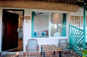a porch with a wooden bench and two chairs at Wallama Villa in Ambalangoda