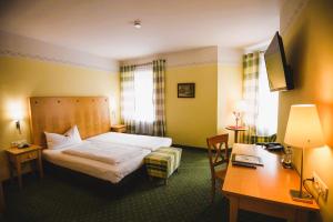 a hotel room with a bed and a desk at Hotel Rosenheimer Hof in Traunstein