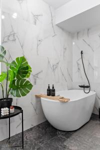 a white bath tub in a bathroom with a plant at Cozy Special City Center - Old Town Apartment with terrace in Bucharest