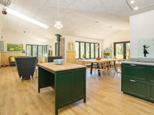 uma cozinha e sala de jantar com armários verdes e uma mesa em Holiday home Sæby CXXV em Sæby