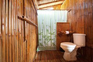 a bathroom with a toilet in a wooden wall at Phuree Hut in Ko Phayam