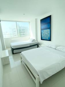 ein weißes Schlafzimmer mit 2 Betten und einem Fenster in der Unterkunft 3tc16 Apartment In Cartagena In Front Of The With Air Conditioning And Wifi in Cartagena de Indias