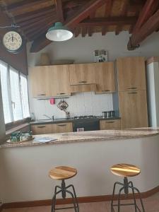 a kitchen with wooden cabinets and two stools at a counter at Il cielo in una stanza in Foligno