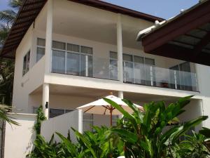 a white building with a balcony with plants at Nakara Residence in Nathon