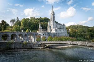 un pont sur une rivière devant un bâtiment dans l'établissement Apparemment T3 55m2, à Lourdes