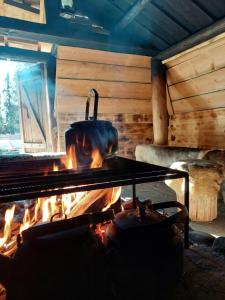 a stove with a pot over a fire in a cabin at ReindeerNook in Kuusamo