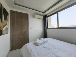 a bedroom with two towels on a bed with a window at Arcadia Beach Continen in Pattaya South
