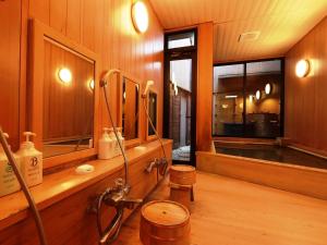 a bathroom with a shower with wooden walls and wooden floors at Ryokan Tanabe in Takayama