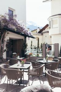 een patio met tafels, stoelen en bloemen bij Genusshotel Goldene Rose in Silandro