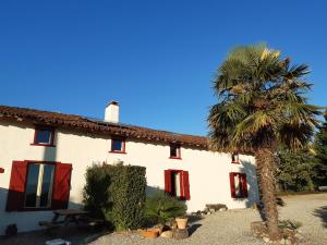 アルティガにあるFerme Beauregard Les Pyrénéesのヤシの木が目の前にある家