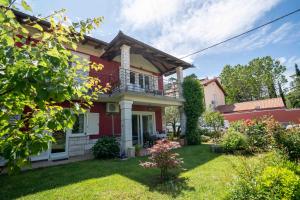 een rood huis met een balkon en een tuin bij Soraja Apartments Izola in Izola