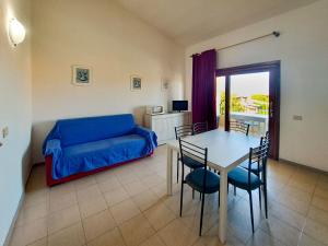 a living room with a blue couch and a table at Centro Residenziale Le Canne in San Teodoro