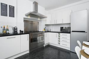 a kitchen with white cabinets and a stove at Huge & Central 3 Bedr, 4 Beds, Covent Gdn in London