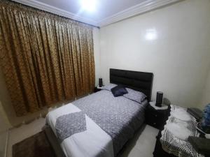 1 dormitorio con 1 cama y una ventana con cortinas en راحتي en Tánger