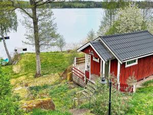 a red cabin on a hill next to a lake at Holiday home LINKÖPING II in Linköping
