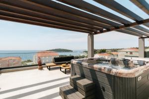 Un jacuzzi al aire libre en una terraza con vista al océano. en Villa LA ZE, en Rogoznica