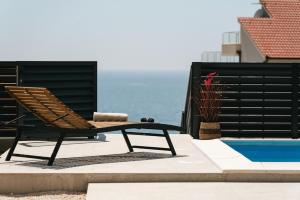 Una tumbona sentada junto a una piscina en Villa LA ZE, en Rogoznica