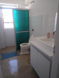 a bathroom with a toilet and a green door at Tacos da Enseada in Guarujá