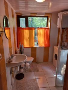 een badkamer met een wastafel en een raam met oranje gordijnen bij Engures māja - mežs un jūra in Engure