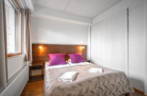 ピュハトゥントゥリにあるSki-Inn PyhäSuitesのベッドルーム1室(大型ベッド1台、紫色の枕付)