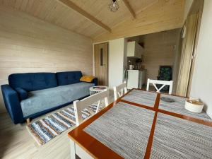 a living room with a blue couch and a table at Urlopownia-Domki z Indywidulanym Ogrodzeniem-Dogfriendly-Duży,Zielony Teren in Gąski
