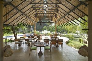 a restaurant with tables and chairs and a large ceiling at Waterwoods Lodge Kabini in Begūr