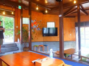 um homem parado numa sala com uma televisão na parede em 青とサイダー em Oshima