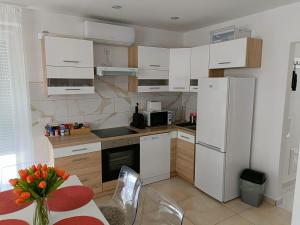 una cocina con electrodomésticos blancos y una mesa con un jarrón de flores en Flower Apartman, 